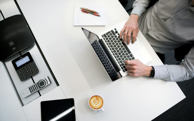 Persona treballant amb un portàtil en un escriptori, vista zenital